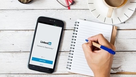 linkedin on smartphone with pen and paper