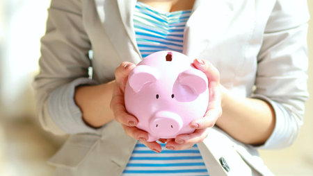 Young woman holding pink piggy bank