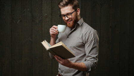 Smiling young man drinking coffee and reading book