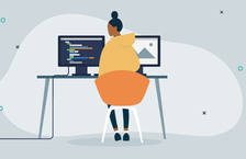 woman programmer at her desk learning programming language in front of computer screens