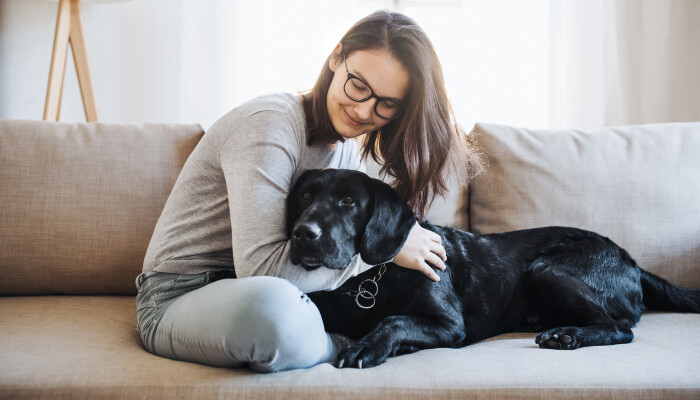 A woman sitting on a couch and hugging a dog