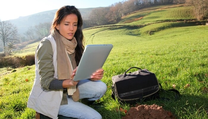 A female scientist looking at a tablet in a field
