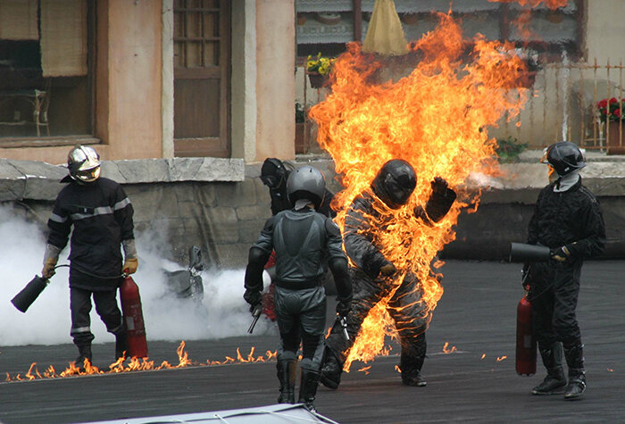 Stunt coordinator worker on a film set, supervising a fire stunt