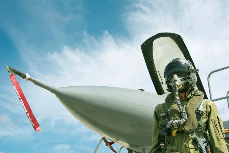 Army pilot standing in front of a fighter jet