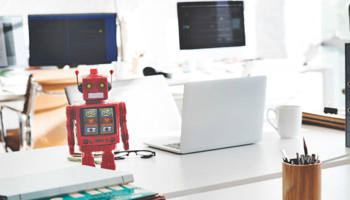 A small red robot standing on a desk